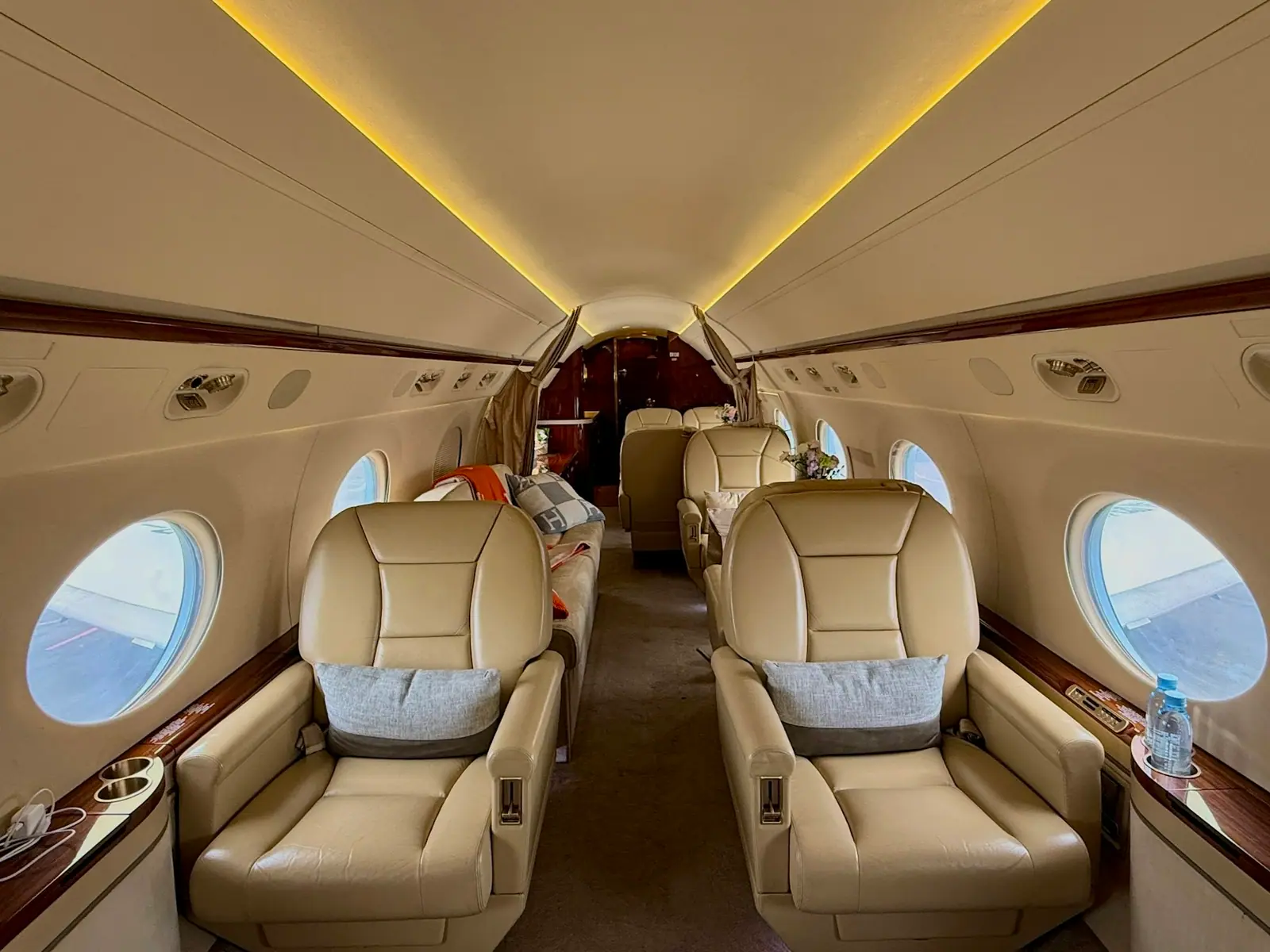 Cabin of a large business jet, cream leather seats and a lit ceiling
