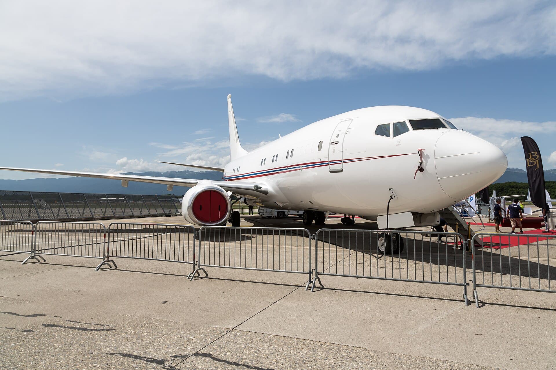 A Boeing Business Jet on static display at the EBACE show in Geneva, behind crowd barriers.